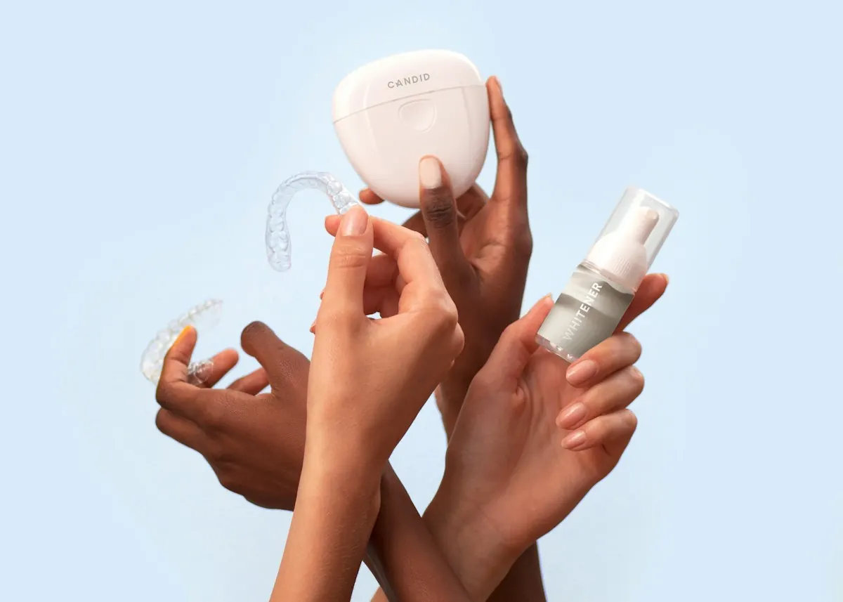 Hands holding clear dental aligners and their case